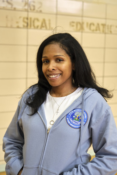 Ms. Greene smiling in PS 262 hoodie in gymnasium