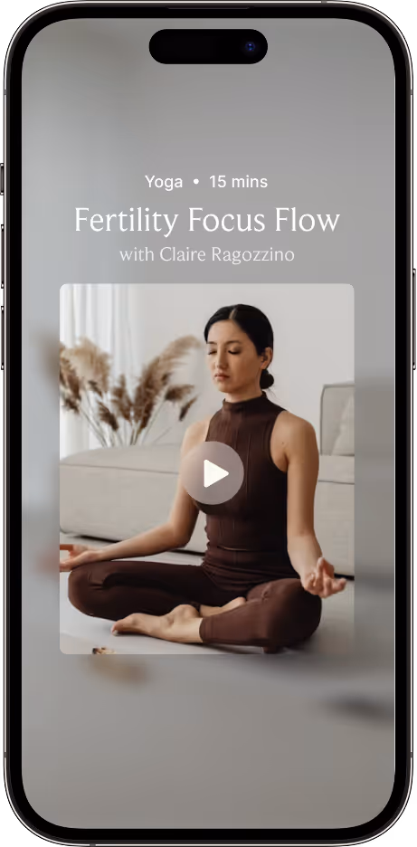 Mobile screen showing a 15-minute yoga video titled Fertility Focus Flow with Claire Ragozzino, featuring a woman meditating cross-legged indoors.