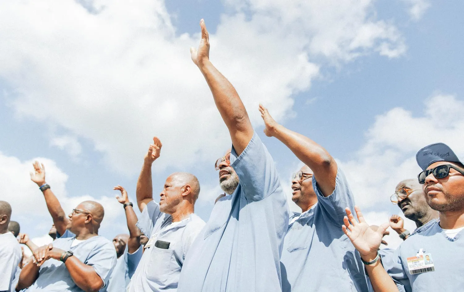 A group of inmates lifting their hands in worship