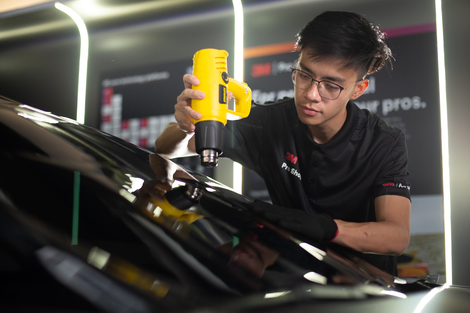 Heat shrinking window film across a curved windscreen, the technique that lets one piece of film follow compound glass curvature.