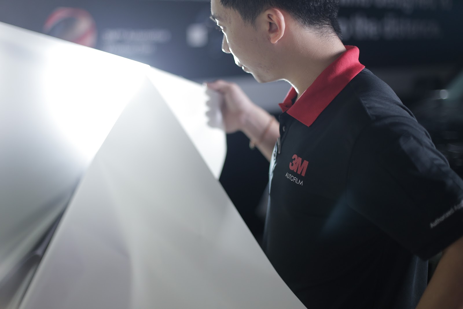 A technician handling a cut sheet of 3M window film, the shaping stage that runs before any window tint installation time is counted.