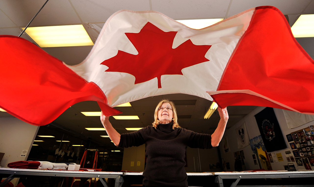 Collage of promotional display products including a blue and yellow custom tent, a round arrangement of small international and pride flags, two feather flags with geometric patterns, and a partially visible pop-up backdrop.
