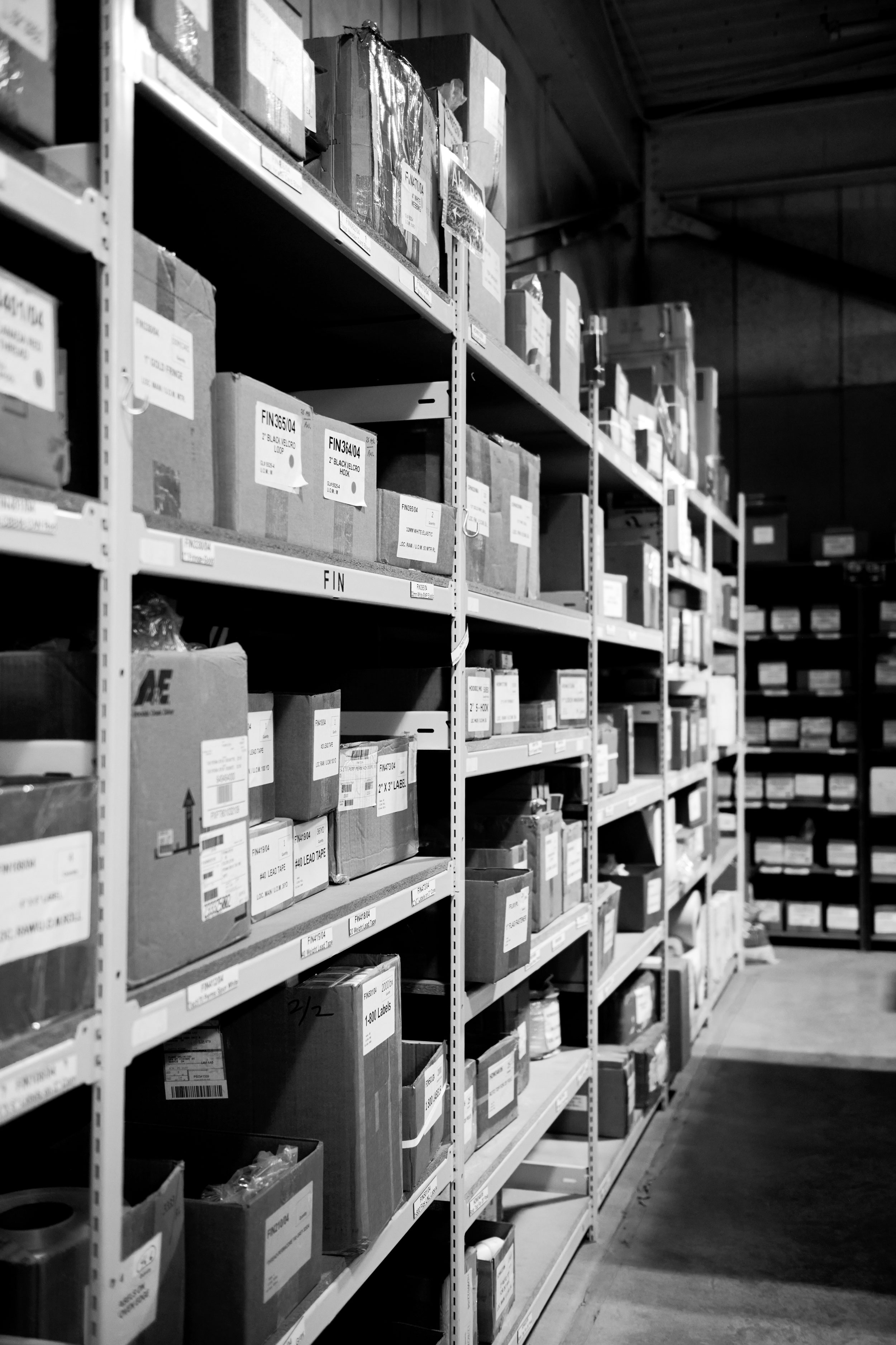 Long warehouse shelves filled with labeled boxes and packages in an organized storage area.