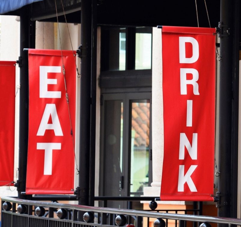 Red vertical banners with white letters reading 'EAT' and 'DRINK' hanging outside a building.