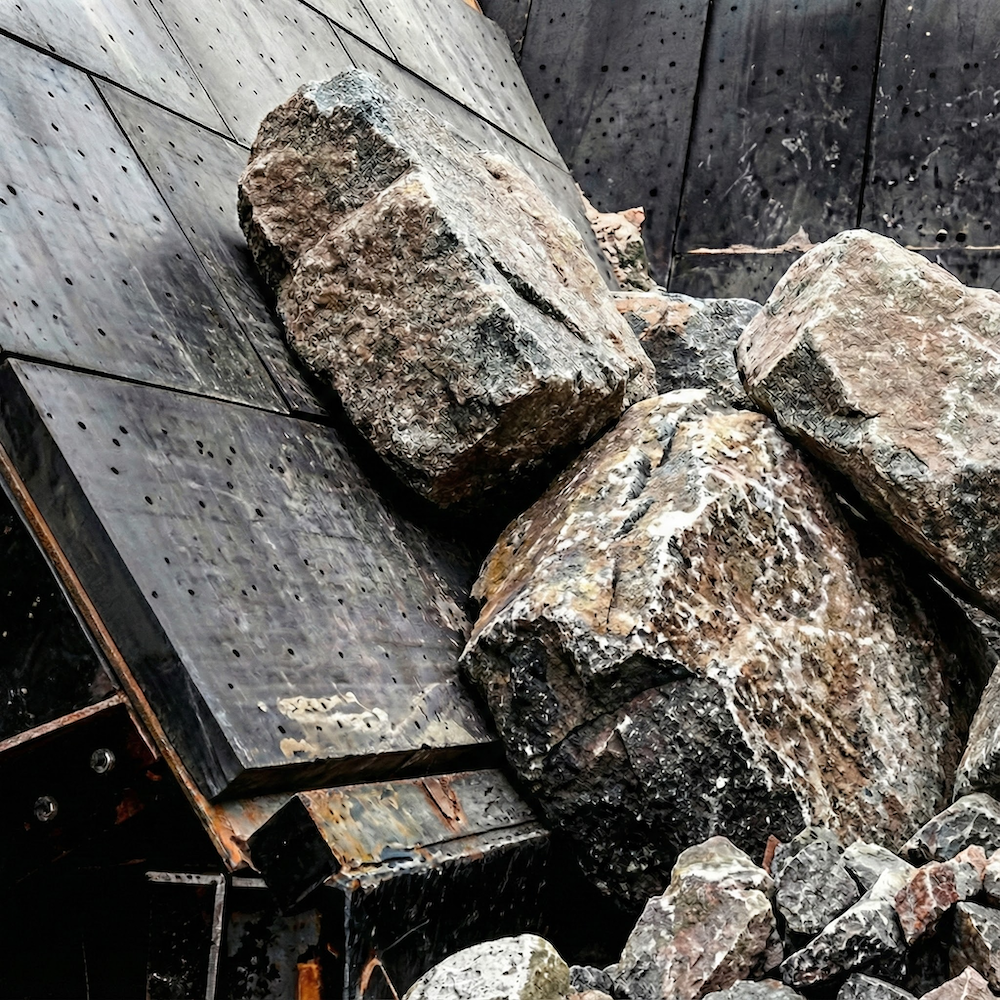 Chute de transfert industrielle subissant l'impact de grosses roches, protégée par des plaques d'usure Élastomont en caoutchouc-céramique de 5 pouces. Une solution d'ingénierie sur mesure fabriquée au Québec pour résister à l'abrasion et faciliter la maintenance.