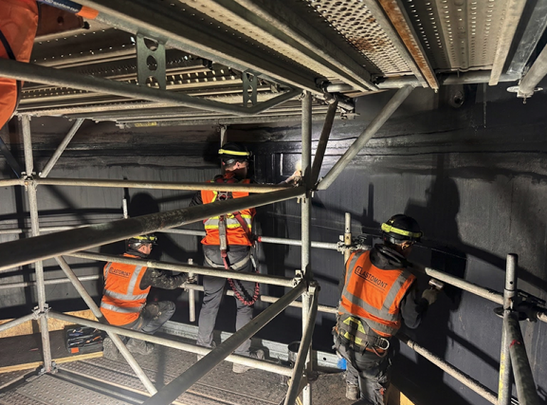 Travail de chantier Elastomont : trois ouvriers sur échafaudage effectuant un rubber lining dans un réservoir.