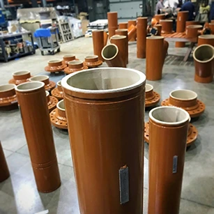 Tuyaux industriels orange dotés d'un revêtement intérieur en caoutchouc naturel beige (tan) 40 duro RS-0013 ou Polycorp T1000, conçus pour le transport de boues abrasives (slurry). Les systèmes incluent des technologies comme Victaulic et Elastomont.