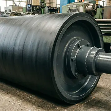 Un grand rouleau industriel avec un revêtement en caoutchouc noir est monté sur un tour mécanique vert dans un atelier de fabrication propre et bien éclairé, montrant le processus de recouvrement.