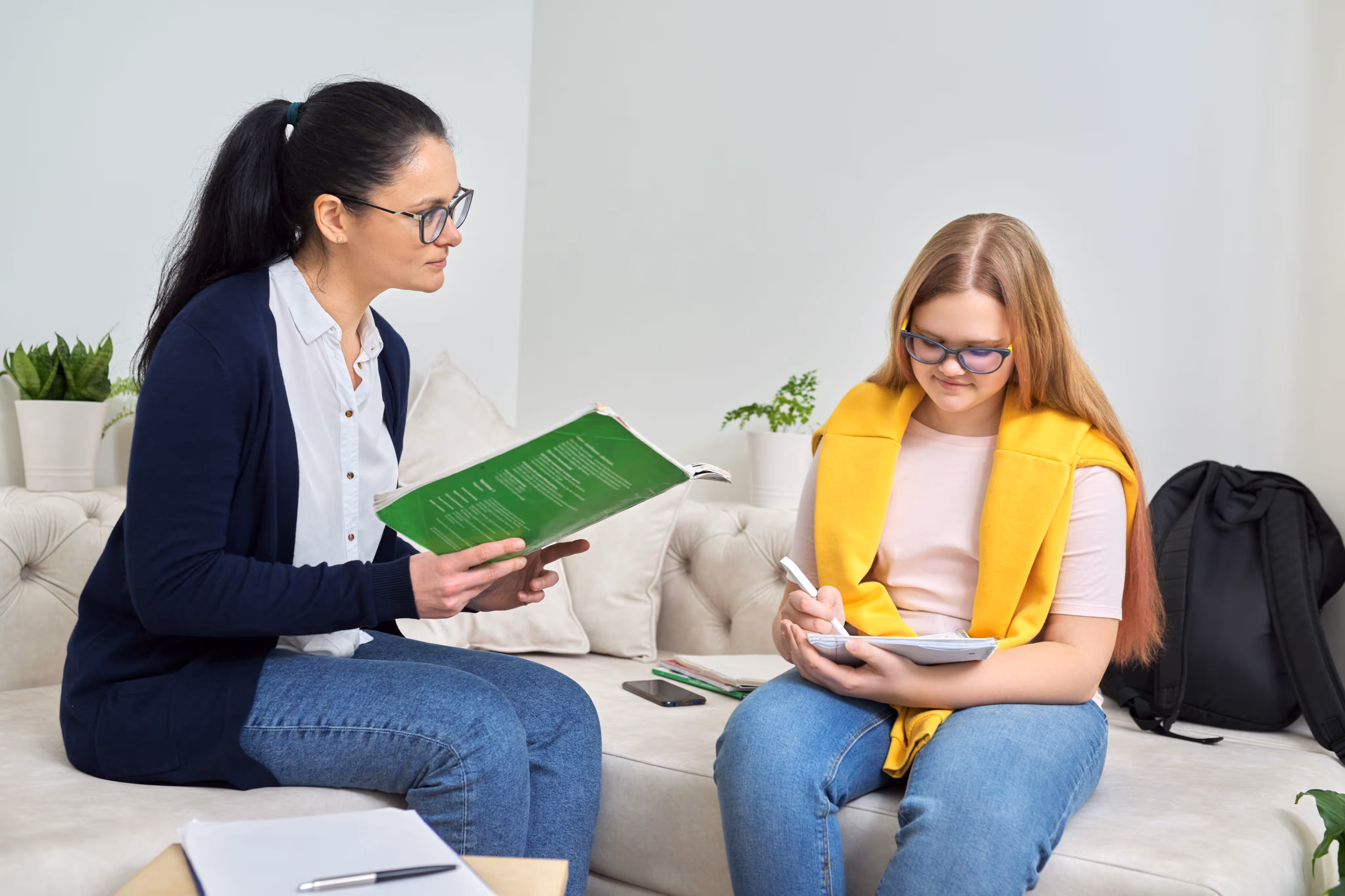 Niña escribe en un cuaderno mientras es atendida en consulta por psicóloga