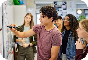 Jóvenes en clase haciendo anotaciones en pizarra blanca