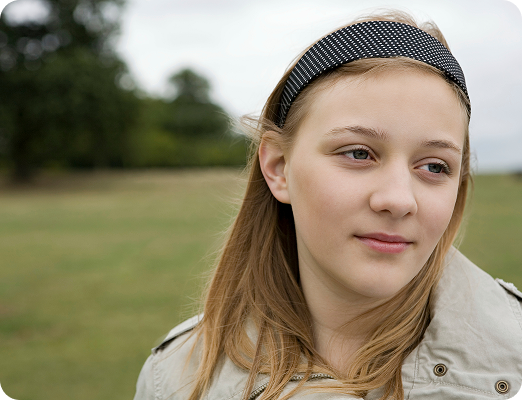 Adolescente pensativa de pie al aire libre en un entorno natural, símbolo de reflexión y proceso interno