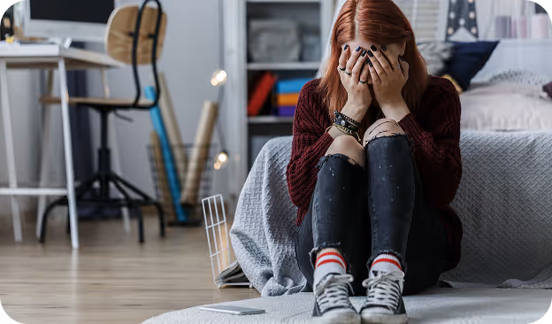 Joven pelirroja con las manos en la cara expresando frustración