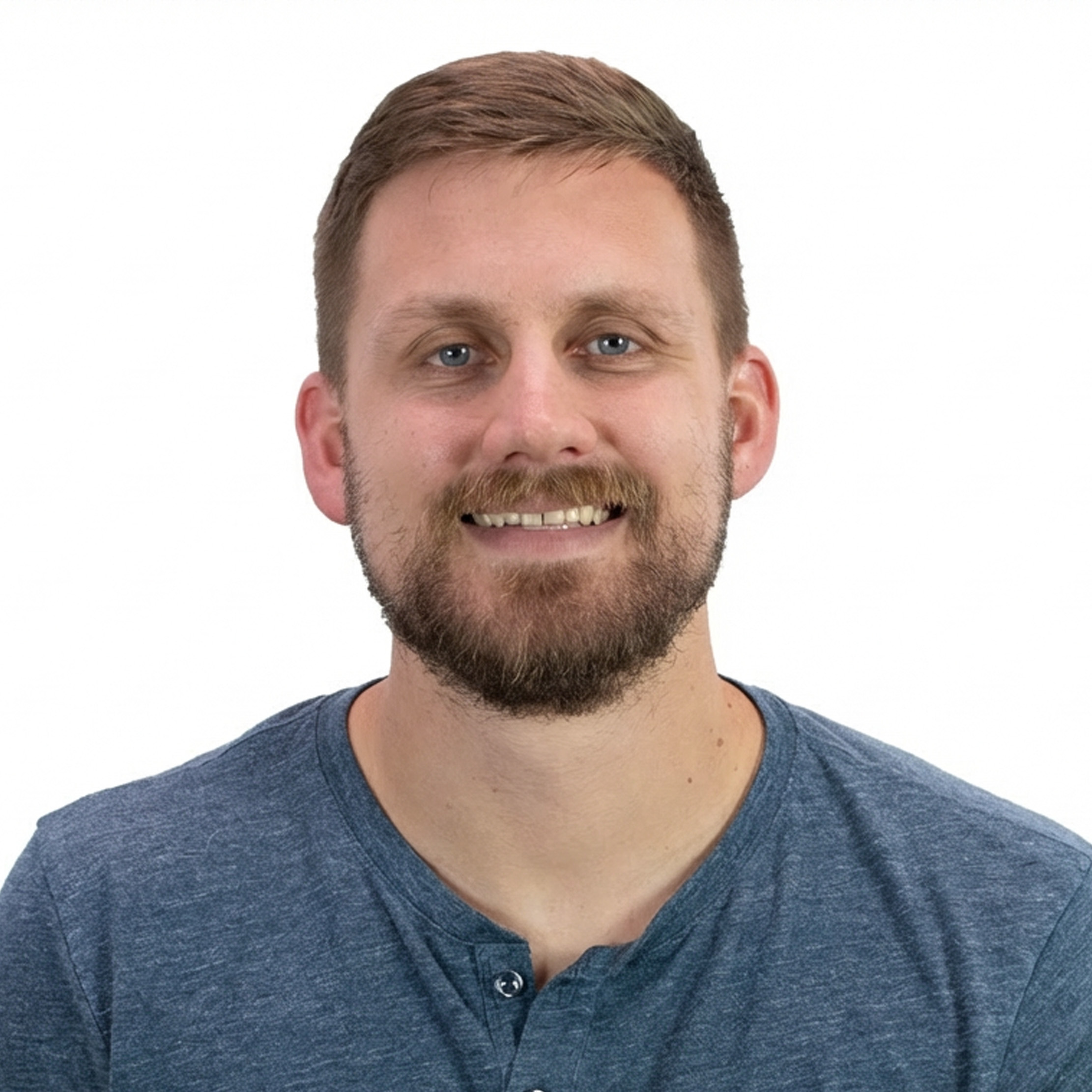 Smiling man with short brown hair and beard wearing a blue shirt against a white background.