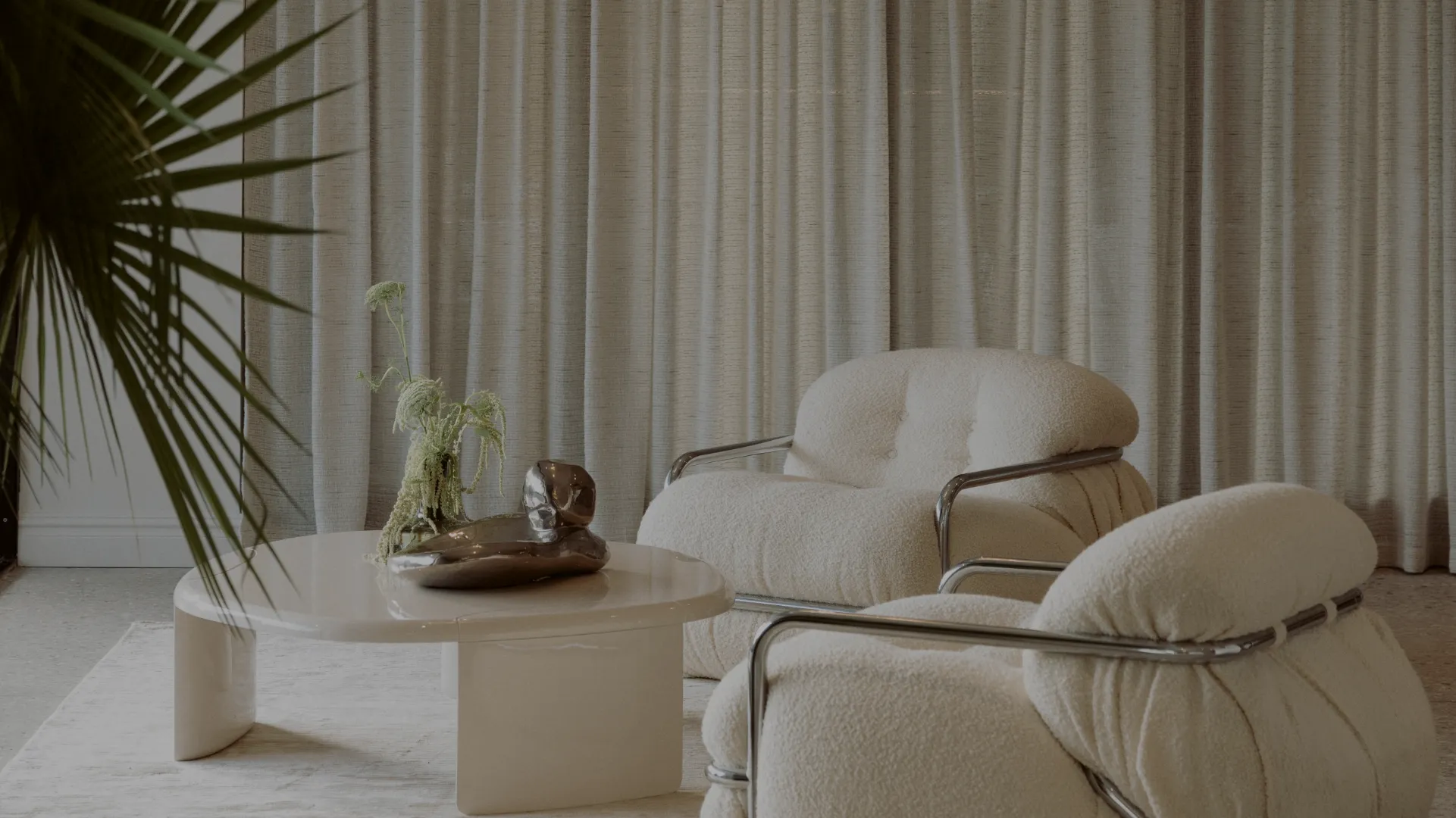 Lounge seating at the Pearl Interiors studio in Noosa Heads, with boucle armchairs and a stone coffee table