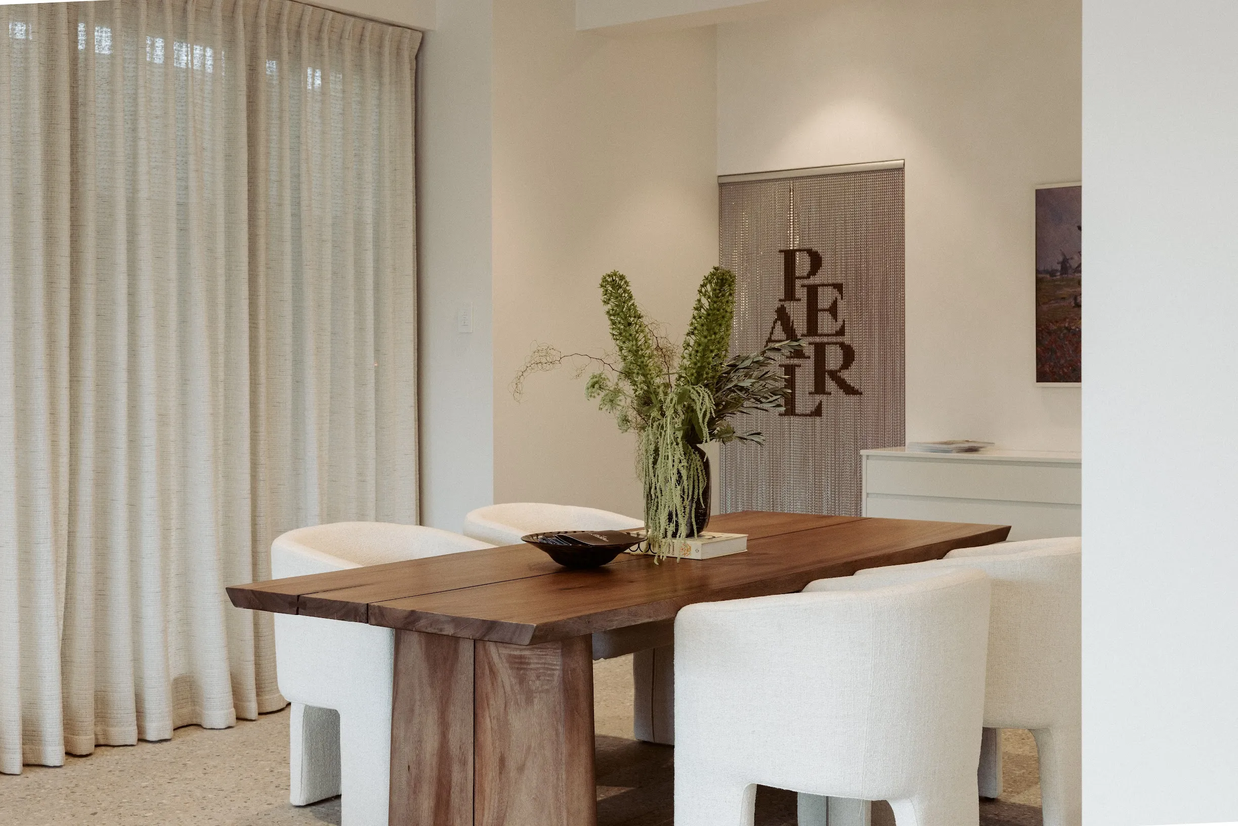 Reception area at the Pearl Interiors studio in Noosa Heads, with a solid timber table, boucle chairs and full-height linen curtains