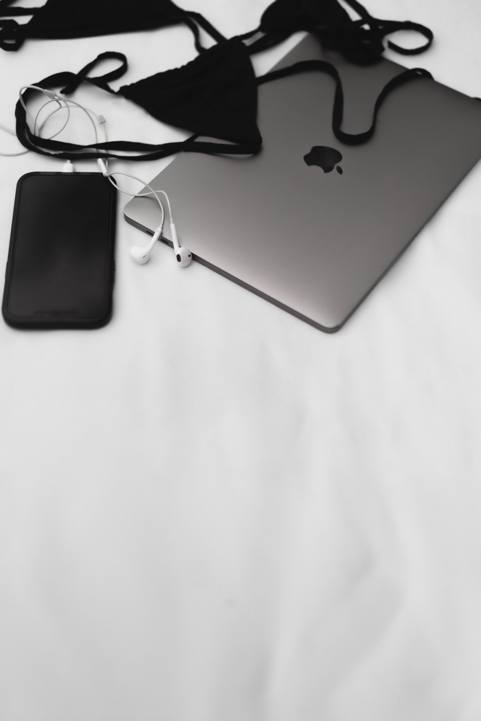 Dark flatlay of laptop, phone and earphones