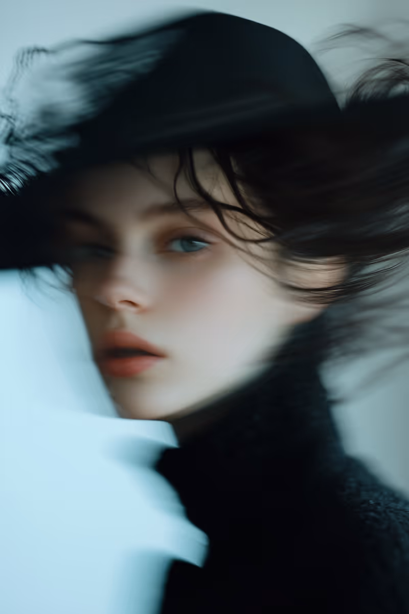 Portrait of a person with blue eyes wearing a black hat and black clothing in soft focus.