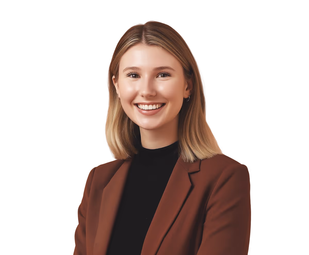 Smiling young woman with blonde hair wearing a brown blazer and black top against a black background.
