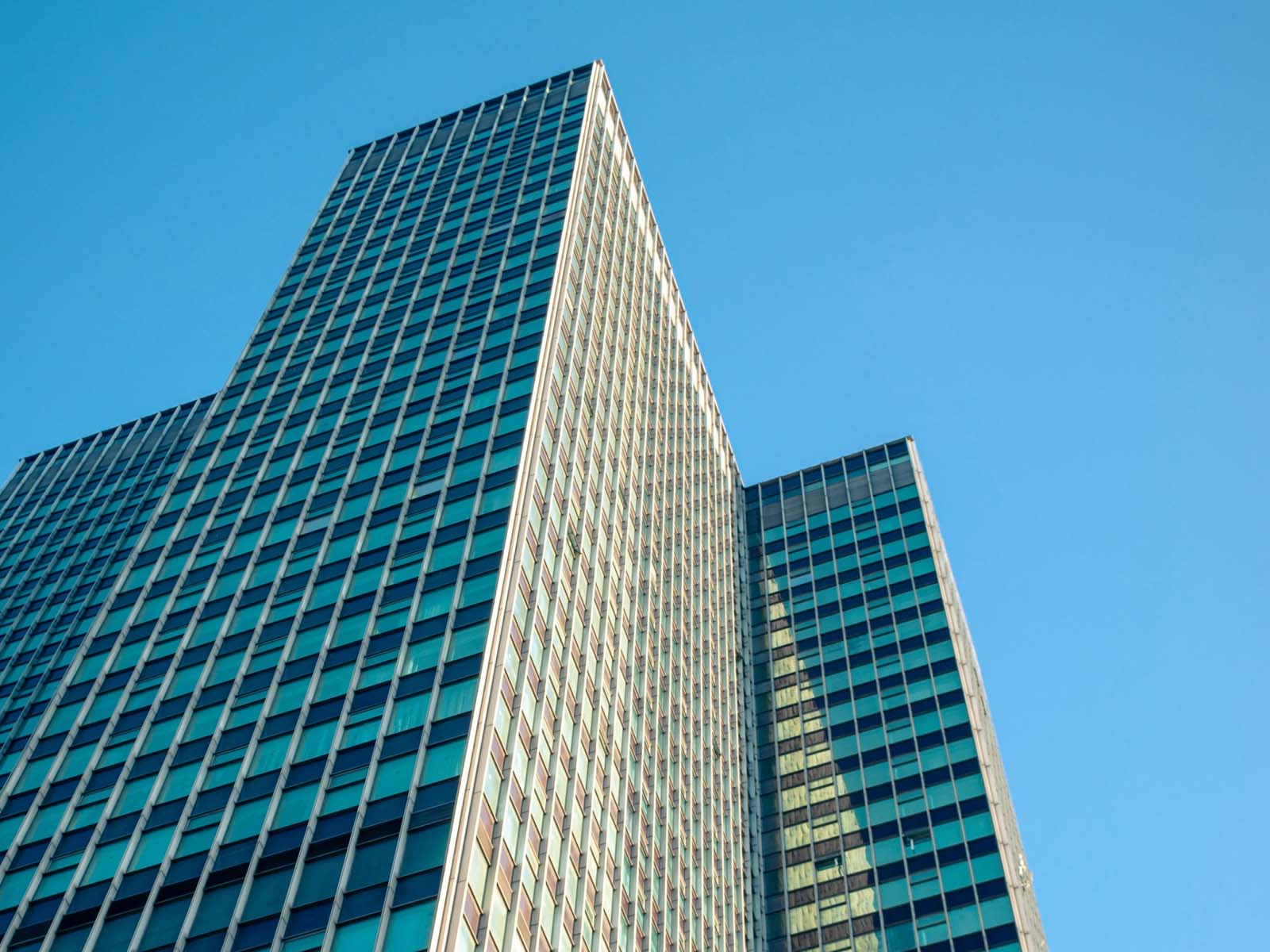 A tall city skyscraper extending into a blue sky.