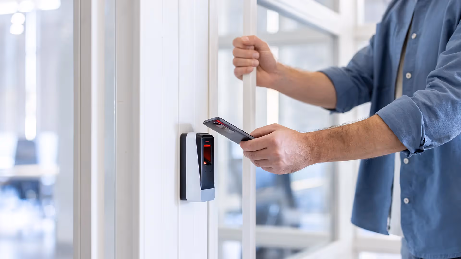 A man using his phone to tap a digital access control lock at his workplace.