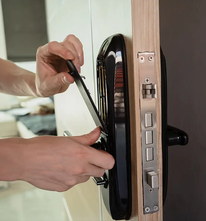 Hands installing or repairing a modern electronic digital door lock