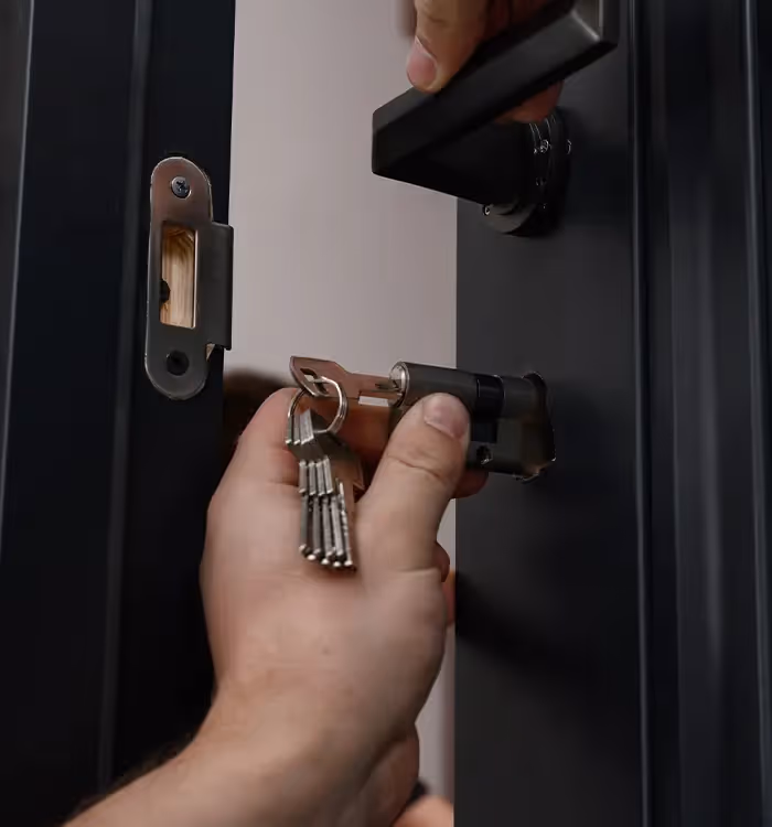 Hand inserting key into door lock with metal keychain