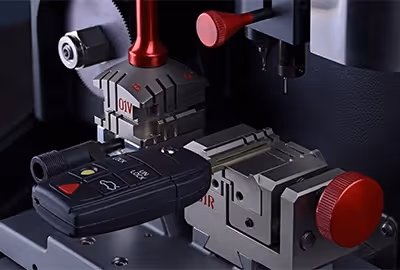 A close-up of a car key being duplicated using a precision cutting machine. 