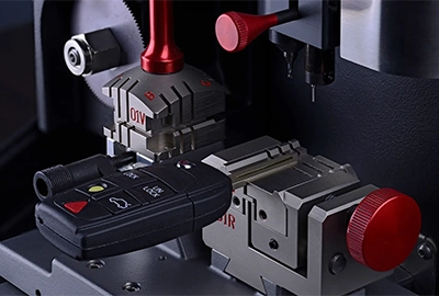 A close-up of a car key being duplicated using a precision cutting machine. 