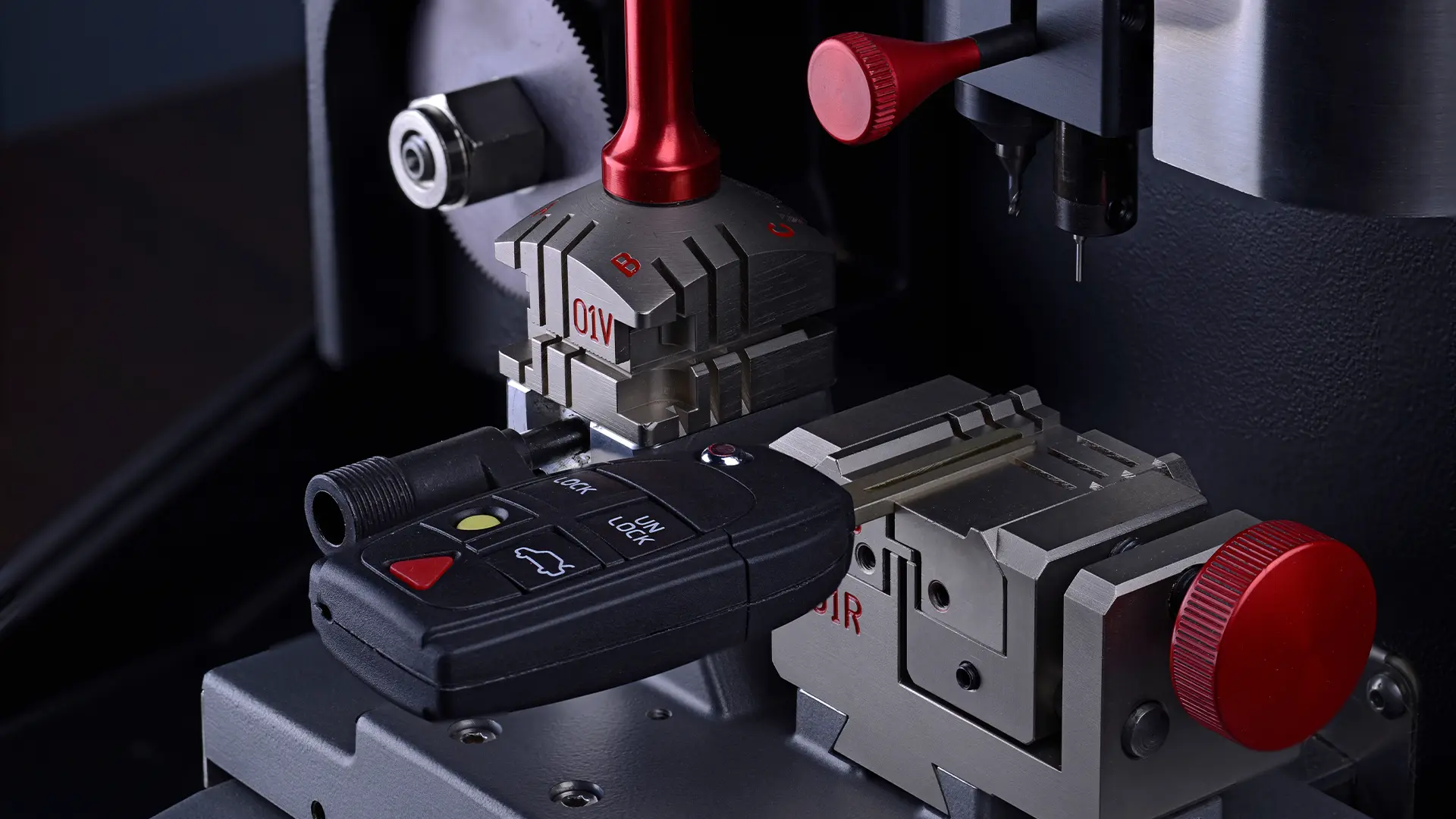 A close-up of a car key being duplicated using a precision cutting machine. 