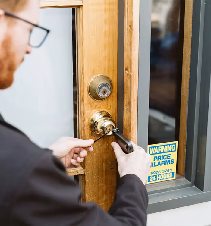 Unlocking a wooden door with a key near a price alarms warning sign