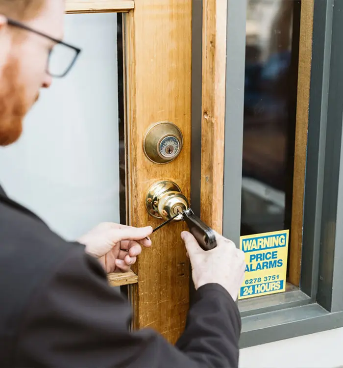 Unlocking a wooden door with a key near a price alarms warning sign
