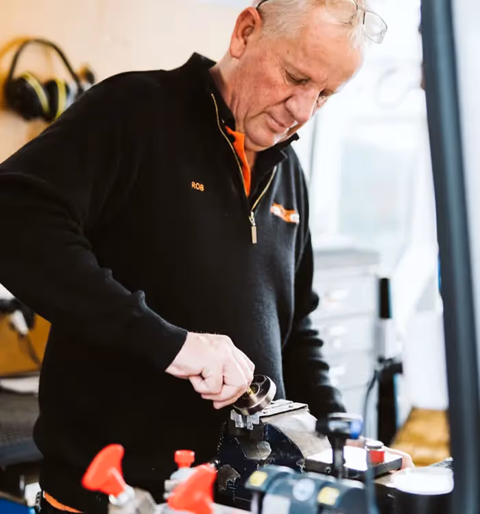 Experienced worker in black jacket operating industrial machinery in workshop