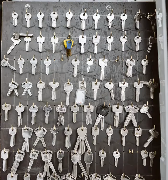 Organized display of numerous metal keys hanging on a gray board