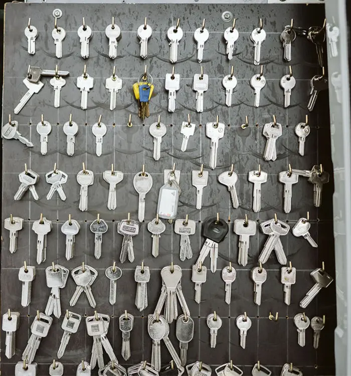 Organized display of numerous metal keys hanging on a gray board