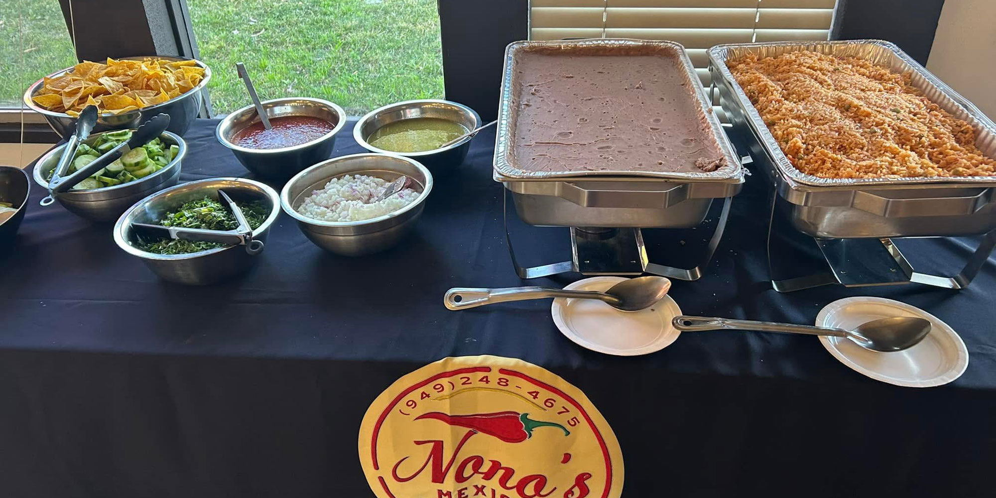 catering table with NONOs Restaurant food - beans, rice and salsas - black cover table - pixelvec