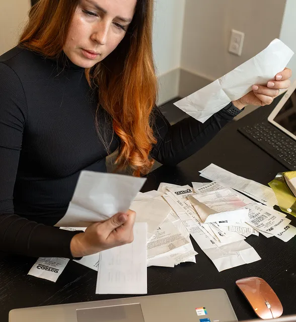 Woman reviewing tax receipts and documents at her desk for tax preparation.