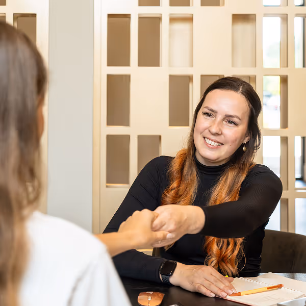 Smiling tax consultant greeting a client with a handshake during a meeting.
