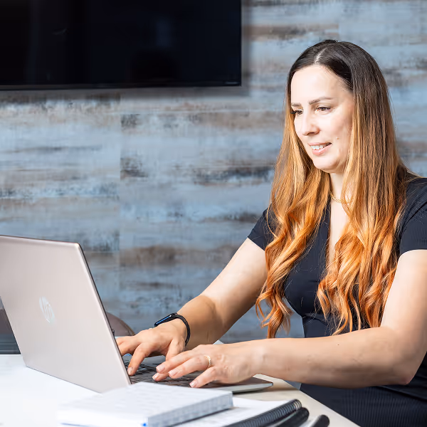 A tax professional working on a laptop while preparing tax documents in an office.