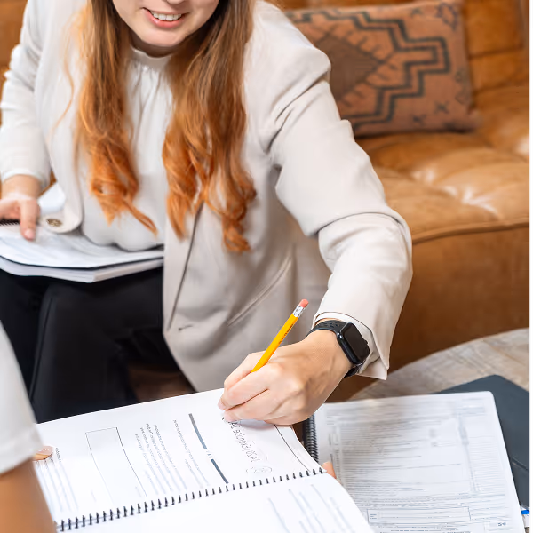 Tax consultant filling out financial documents with a pencil during a client meeting