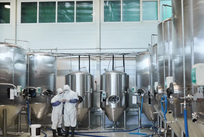 people in full protective dress, inside of a liquid chemical storage facility