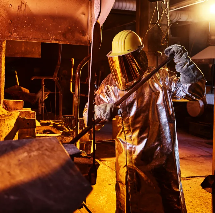 Man in protective work ware, operating a metal furnace