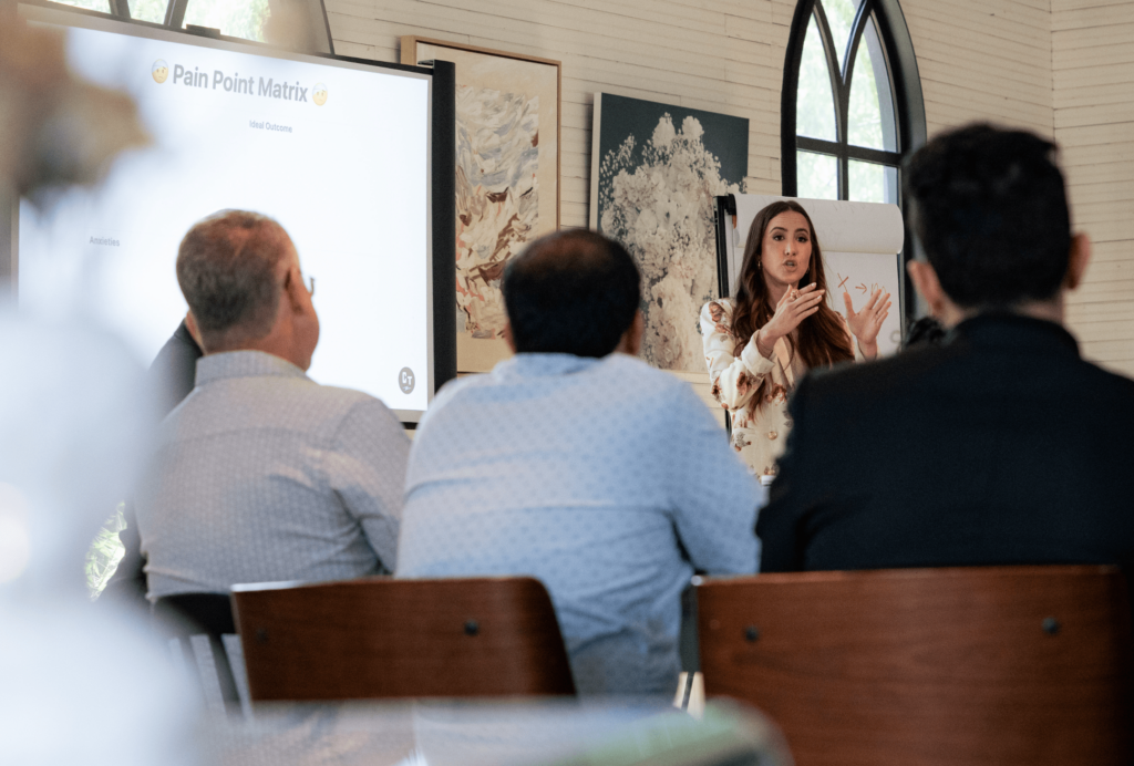 Codie Sanchez leading a workshop session explaining the Pain Point Matrix to attendees.