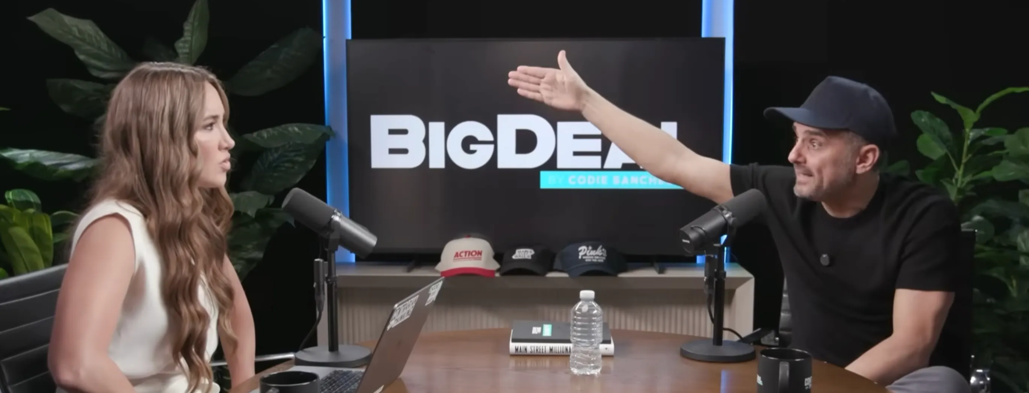 Gary Vaynerchuk and Codie Sanchez talking on the Big Deal podcast set. Gary is passionately gesturing while Codie listens attentively.