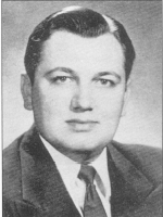 Black and white portrait of a man wearing a suit and tie, with neatly combed hair, facing the camera directly.