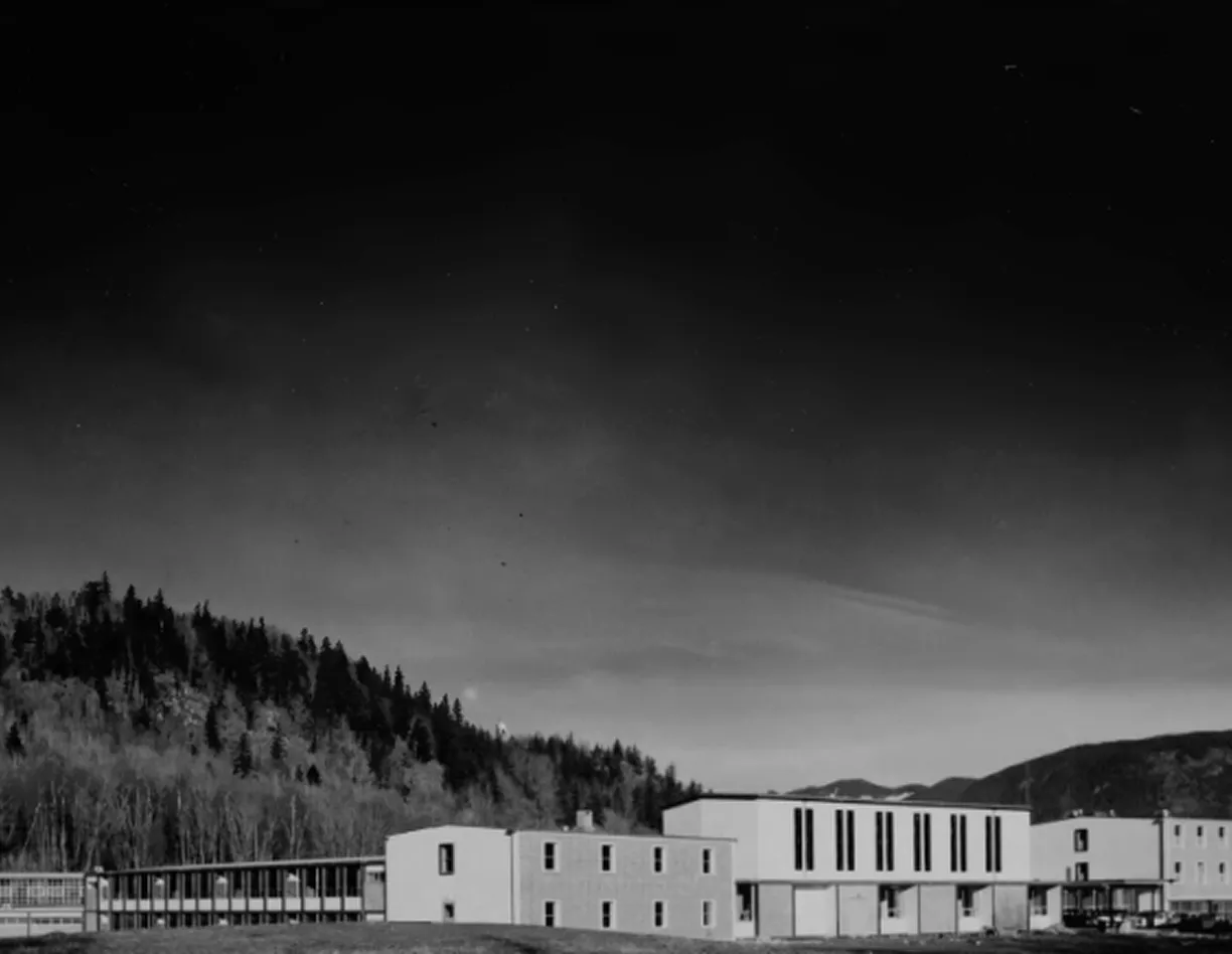 A black and white photo of a building with mountains in the background.
