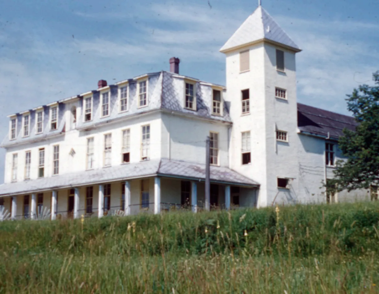 A large white building sitting on top of a lush green field.