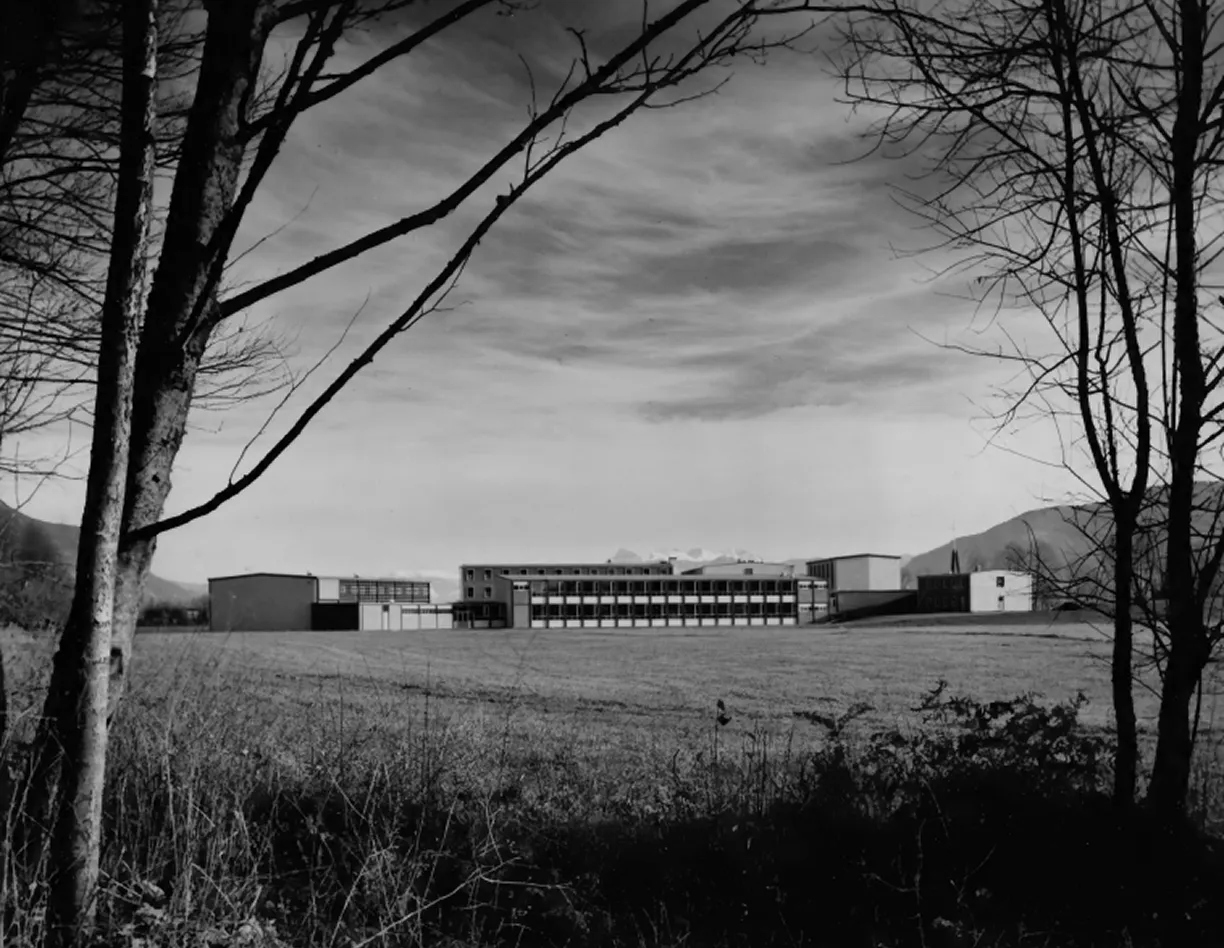 A black and white photo of a building in a field.