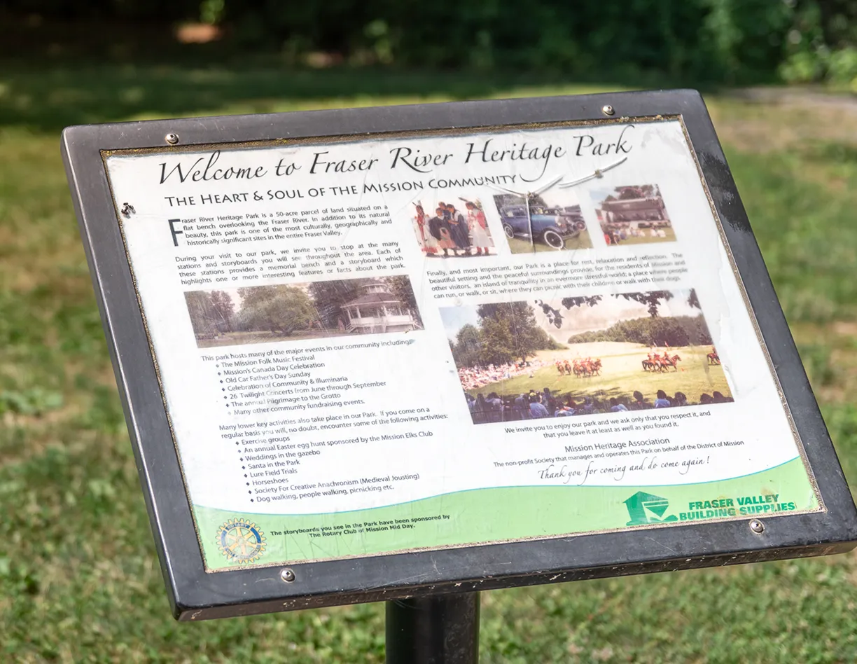 A sign in front of a grassy field.