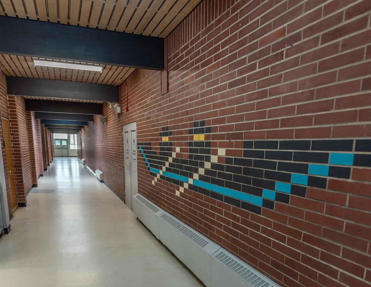 A hallway with a brick wall and a painting on the wall.