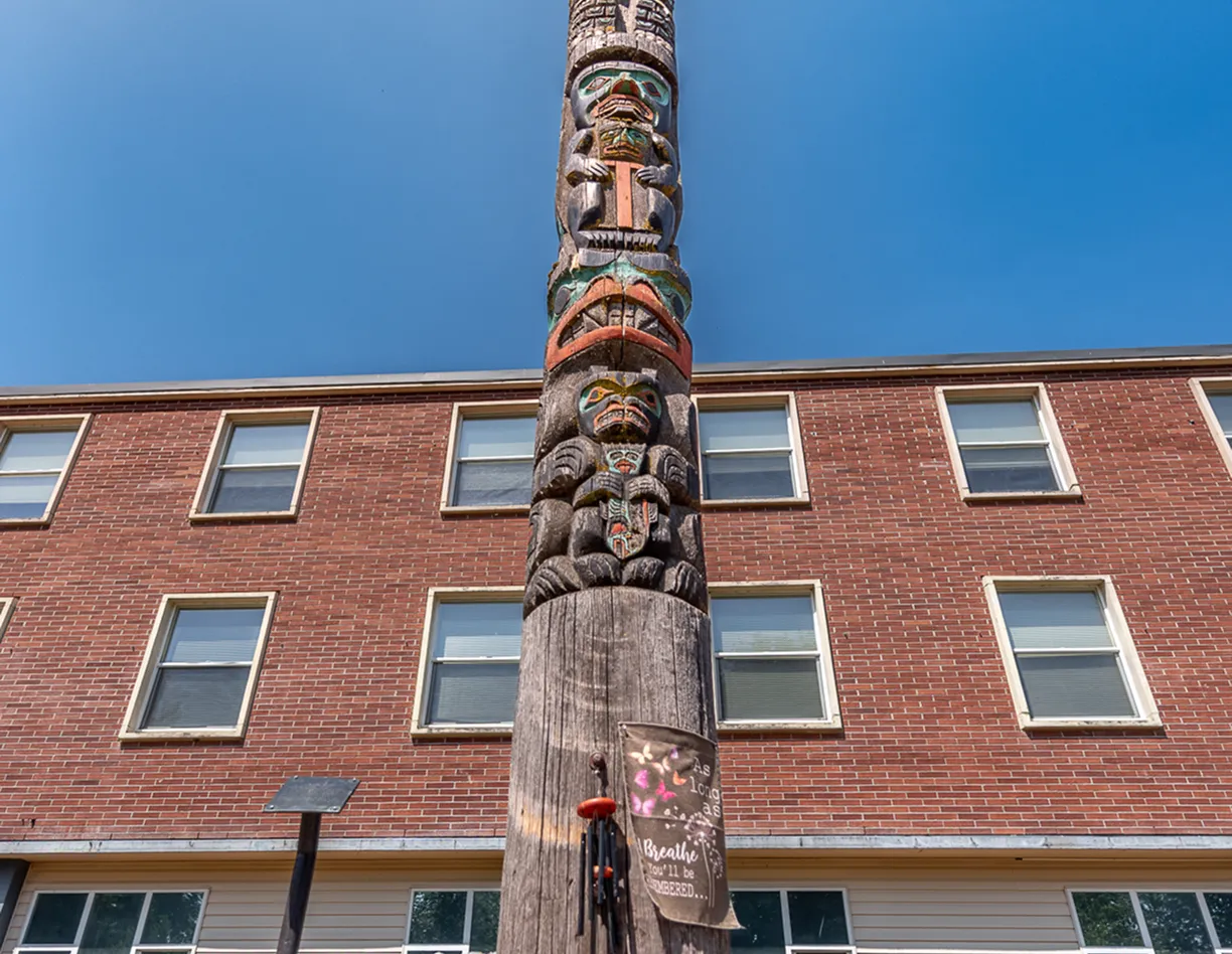 A totem pole in front of a brick building.